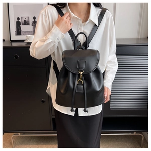 Détail du sac à dos noir en similicuir avec boucles dorées et fermeture à cordon