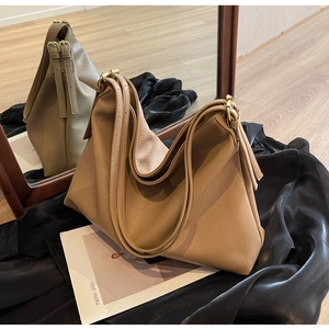 Detail of khaki pebbled leather hobo bag with adjustable strap on silk background