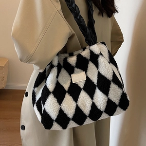 Plush checkerboard tote bag with black woven handles shown styled on a model in autumn