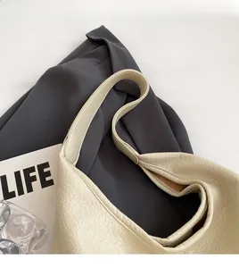 Detailed close-up of cream textured leather bucket bag with wide shoulder strap