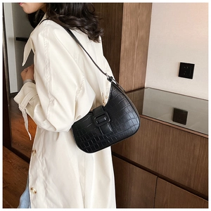 Detail of black crocodile pattern hobo bag with large buckle on a white trench coat