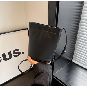 Vue détaillée d'un sac seau en cuir noir avec bandoulière réglable et finition mate élégante