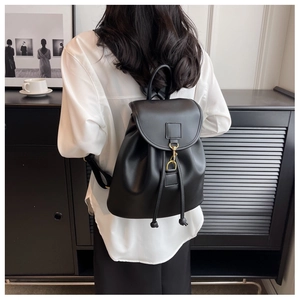 Sac à dos moderne en cuir noir avec rabat et boucle dorée porté par un mannequin