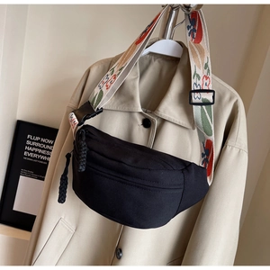 Detail of black canvas waist bag featuring wide adjustable strap with floral patterns