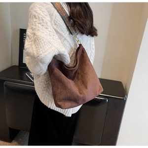 Detail of hobo bag with ethnic embroidery strap and dark brown suede texture