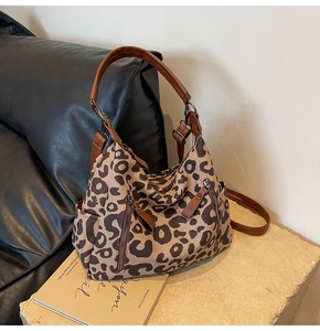 Détail du sac hobo léopard en toile avec lanières en cuir marron et fermetures éclair