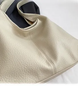 Close-up of cream large-capacity tote bag showing litchi grain texture and precise stitching