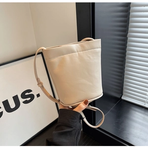 Détail d'un sac seau en cuir beige crème avec une fine bandoulière réglable et chic