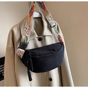 Close-up of black canvas crossbody bag featuring a colorful floral embroidered wide strap