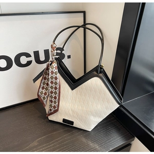 Close-up of off-white woven texture tote bag with black trim and a decorative silk scarf
