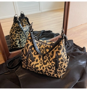 Détail du cabas en toile léopard avec fermetures éclair en métal et anses en cuir noir