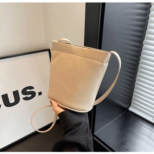 Gros plan sur le sac seau beige minimaliste avec coutures décoratives et fine bandoulière