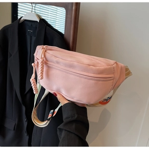 Detail of pink canvas chest bag with decorative woven puller and ethnic patterned strap