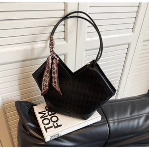 Detail of black quilted tote bag with V-shaped opening and decorative silk scarf