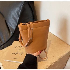 Détail de la bandoulière réglable et boucle argentée sur un sac seau minimaliste marron
