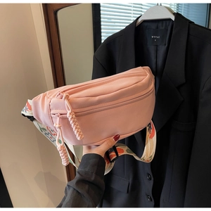 Detailed shot of pink canvas chest bag with colorful printed strap and woven zip pulls