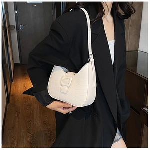 Detail of cream white underarm bag featuring faux crocodile texture and a large square buckle
