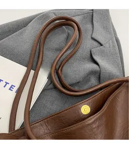 Detail of smooth shoulder strap and golden magnetic buckle on dark brown leather tote bag