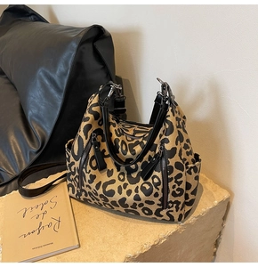 Détail du sac cabas en toile léopard avec anses en cuir noir et poche zippée devant