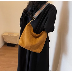 Detailed view of brown suede tote with vintage woven strap and golden metal buckle