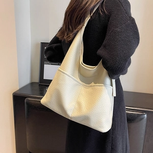 Grand sac hobo blanc cassé en cuir grainé avec poches extérieures porté à l'épaule