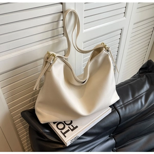 Detail of cream white pebbled leather hobo bag with adjustable gold-tone buckle strap