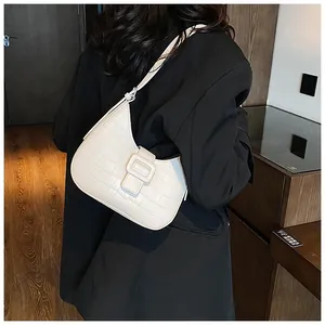 Detailed view of white crocodile pattern underarm bag on model for size perspective