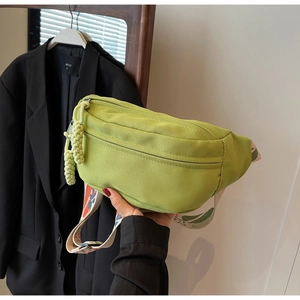 Detail of bright green canvas crossbody bag featuring floral embroidery wide strap