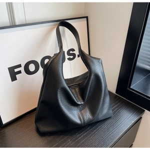 Detailed macro view of black pebbled leather tote bag showing soft texture and stitching
