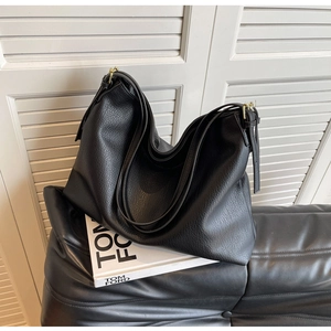 Detail of black pebbled leather texture and gold metal buckle on large hobo tote bag