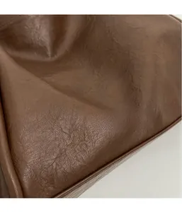 Detailed close-up of brown textured leather stitching and smooth edge finish on the tote bag