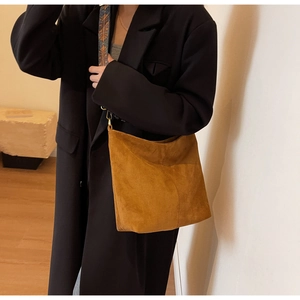 Detail of vintage brown suede tote bag featuring a colorful geometric patterned strap
