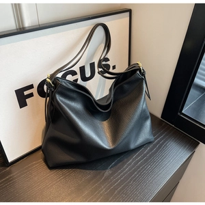 Macro shot of black hobo bag with pebble leather texture and golden metal buckle detail