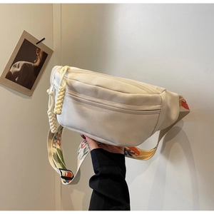 Detail view of beige canvas waist bag featuring vintage floral embroidery on the wide strap