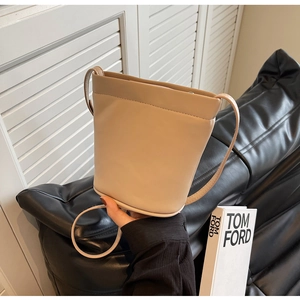 Détail du sac seau en cuir crème sur canapé noir avec éclairage naturel doux