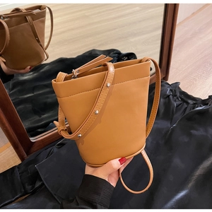 Détail du sac seau marron en matière lisse avec rivet argenté sur la bandoulière
