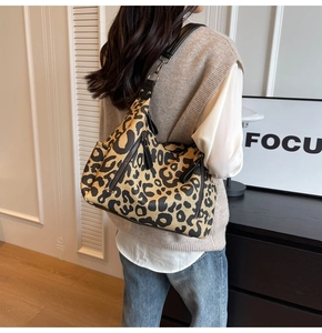Détail du sac cabas en toile à imprimé léopard avec fermetures éclair noires et bandoulière