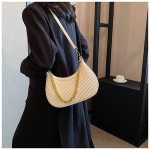 Détail d'un sac demi-lune plissé avec une chaîne dorée et du cuir PU de couleur crème