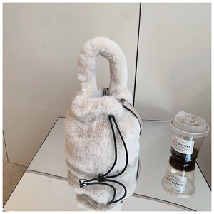 Détail d'un sac seau en fausse fourrure crème avec cordon de serrage et anse douce