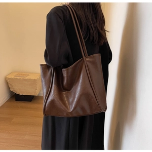 Macro detail of deep brown leather tote bag with smooth texture and sturdy shoulder strap