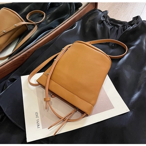 Détails du sac seau camel avec rivets argentés et cordon sur tissu satiné élégant