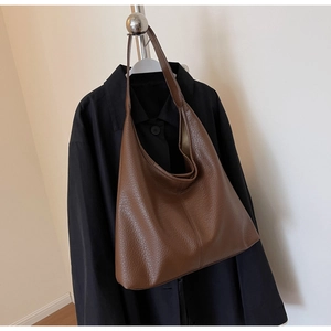 Detail of a large brown tote bag with premium lychee grain texture and wide shoulder strap