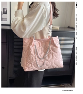 Détail d'un sac cabas en nylon rose matelassé avec motifs cœurs et bandoulière en chaîne