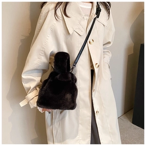 Gros plan du sac seau en peluche noire avec bandoulière en cuir porté par un mannequin