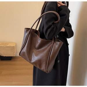 Detail of the vintage dark brown faux leather tote bag with soft texture and long handles