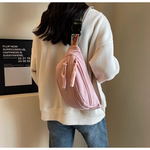 Pink canvas crossbody chest bag shown on model with ethnic woven strap and soft pink tones