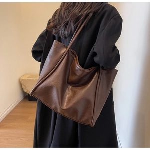Macro shot of large dark brown tote bag showing supple leather texture and slouchy shape