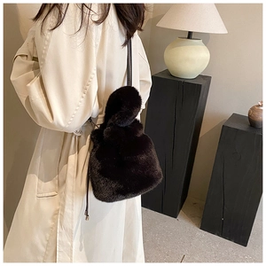 Sac seau en fausse fourrure noire porté sur un trench beige pour un style hivernal chic