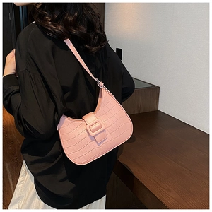 Detail of pink hobo bag featuring crocodile embossed texture and decorative buckle strap