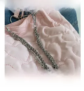 Détail du sac cabas en nylon matelassé rose avec coutures en cœur et chaîne en métal argenté